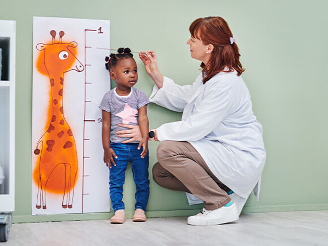 Doctora revisando el crecimiento de una niña.