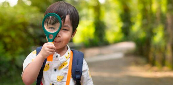 Niño jugando con una lupa.